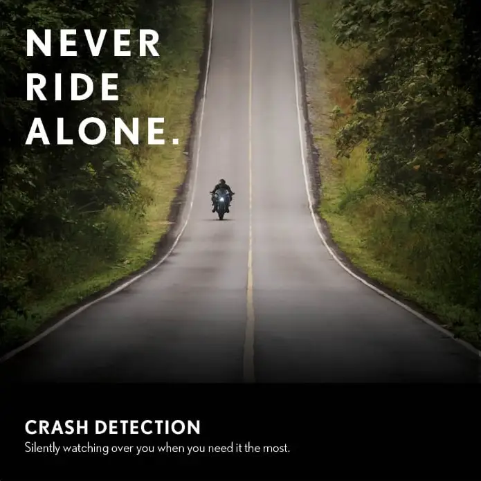 Lone motorcyclist on a winding road, highlighting the cardo packtalk pro's crash detection feature for rider safety, with text 'Never Ride Alone'.