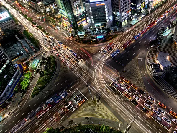 Urban-Area Aerial view of a busy city intersection at night, with long exposure light trails from vehicle traffic.